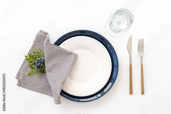 Obraz Festive table setting with empty plate and glasses, cutlery and napkin - green leaves decorated, flat lay. Top view
