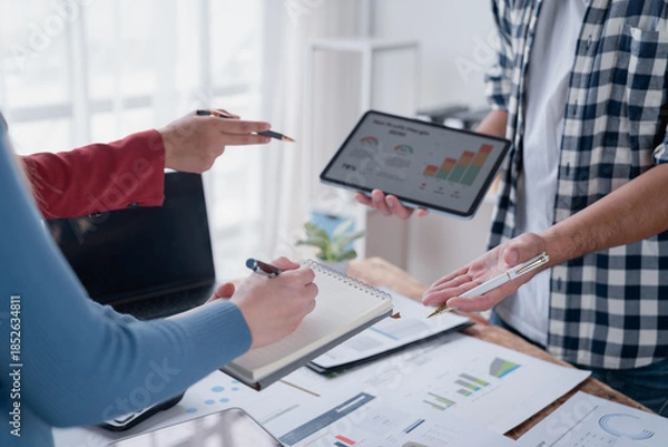 Fototapeta Business team analyzing financial data on tablet and documents