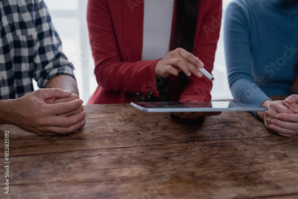 Fototapeta Colleagues collaborating using digital tablet at wooden table