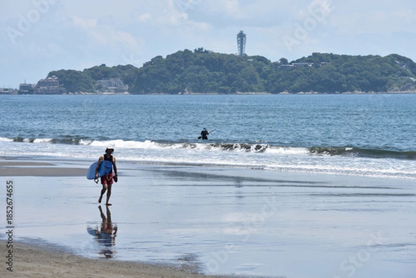Fototapeta 潮が引いた片瀬西浜海岸で海に入るサーファー
