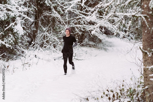 Fototapeta Young man running in the snow in Austria