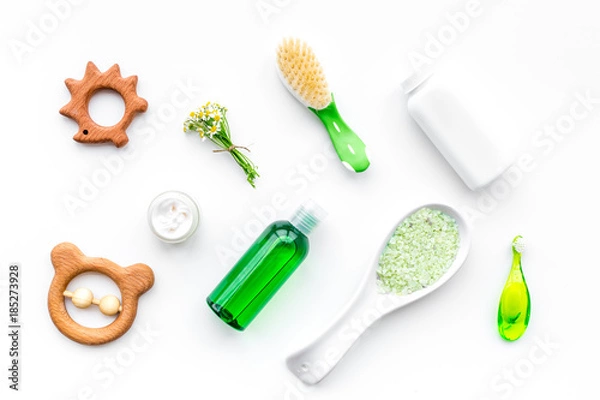 Fototapeta Soft bath cosmetics for kids with chamomile. Bottles, spa salt, tooth brush and toy on white background top view