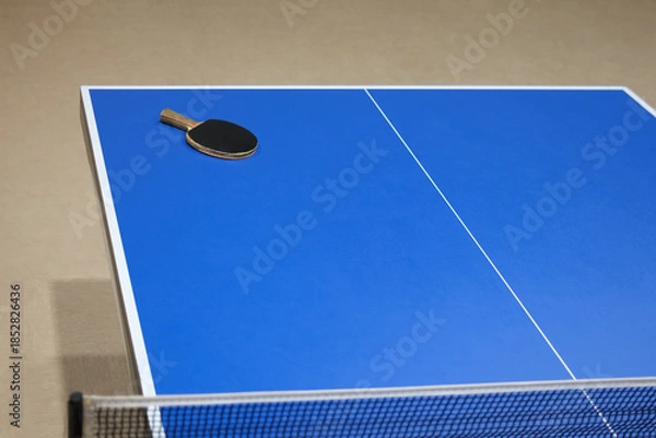 Fototapeta A blue ping pong table with a net and a racket