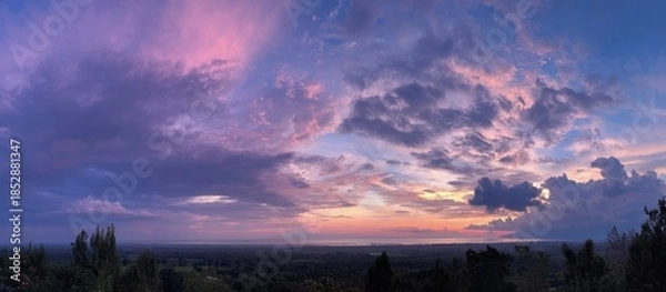 Obraz Panoramic dusk scene. Pink, purple, and blue clouds dominate sky, overlooking a dark landscape