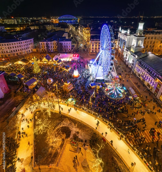 Fototapeta Aerial drone view of a festive Christmas market with a large illuminated tree.