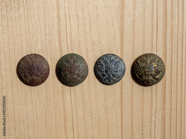 Fototapeta Buttons in the form of a soldier of the Russian Empire. Archaeological finds on an ancient battlefield. Copper and lead buttons with a double-headed eagle