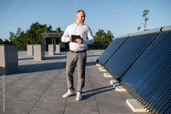 Obraz Man using technology to inspect rooftop solar installation