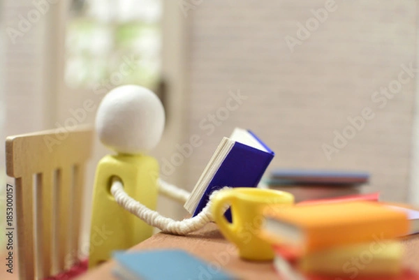 Obraz 読書をする木製人形の写真　積まれた本　趣味の時間　勉強　ミニチュア