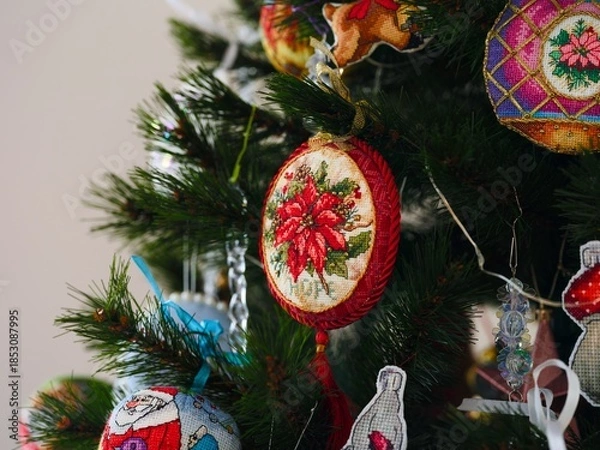 Obraz A close-up shot of handmade cross stitched Christmas ornaments featuring an embroidered poinsettia design hanging on a Christmas tree. All Christmas ornaments embroidered and made by myself.