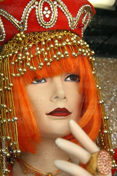 Obraz female mannequin head with eye liner, lipstick, orange wig and vintage beaded costume hat