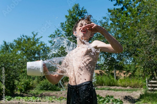 Obraz A teenage boy is doused with water