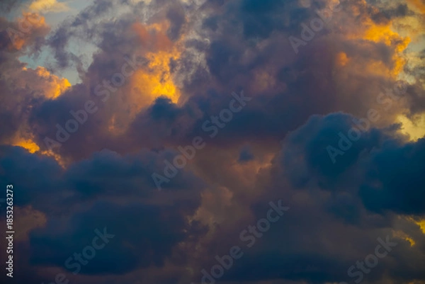 Obraz Beautiful evening sky filled with heavy cumulus clouds illuminated by the setting sun
