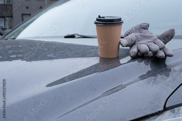 Fototapeta Disposable coffee cup and warm gloves resting on car hood