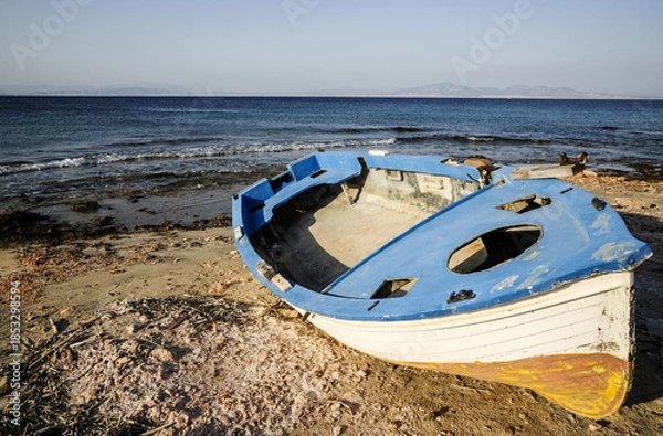 Fototapeta An old Greek boat on the Mediterranean shore on the island