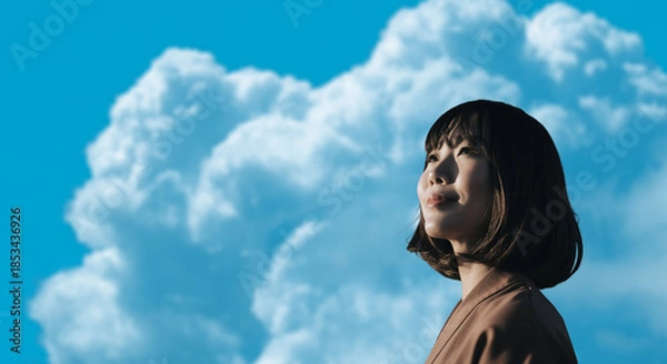 Obraz 春・上を見上げ微笑む明るい表情の日本人女性の顔　前向きでポジティブ希望に満ちた表情　就職・新生活・旅行・リラックス・入学のイメージ　青空と雲の背景