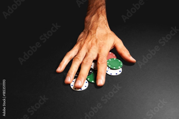 Obraz Man's hand holding green and red poker chips on a black background
