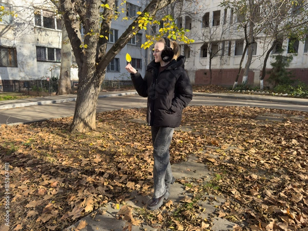 Fototapeta Woman autumn leaf smiles holding yellow foliage during sunny cold day