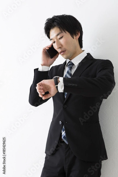 Fototapeta 電話しながら時計を見る若いビジネスマン