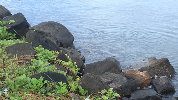 Obraz Rocks are arranged on the edge of the beach, the sea water is calm