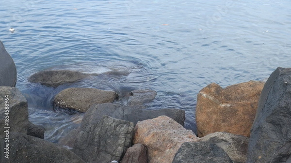 Obraz Rocks are arranged on the edge of the beach, the sea water is calm