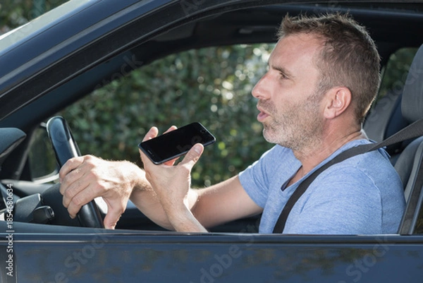 Obraz man using his phone while driving the car