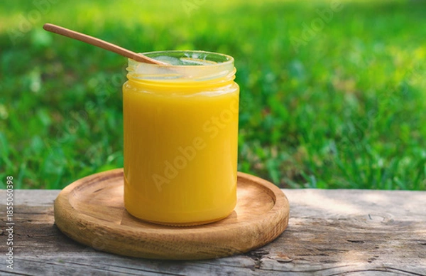 Obraz Ghee in a jar in a meadow. Selective focus.