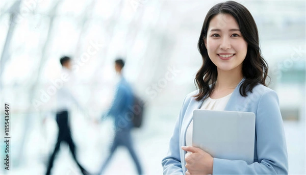 Obraz オフィス街の通路でパソコンを持ち微笑むビジネス女性