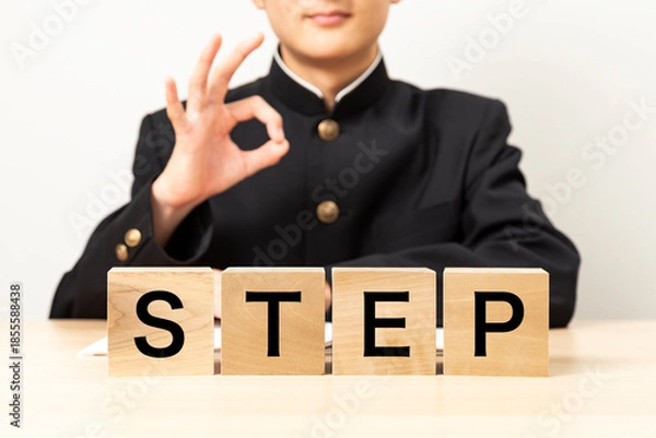 Fototapeta 「STEP」と書かれたブロックとOKサインをする男子学生