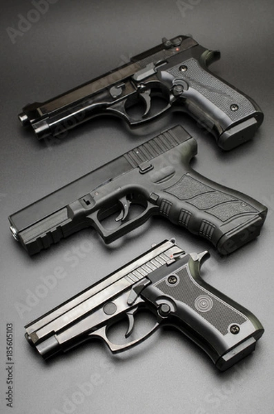 Fototapeta three black pistols on a black background.