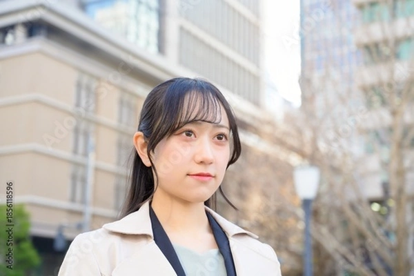 Fototapeta スーツを着てビル街に立つ20代フレッシャーズのビジネスウーマン
