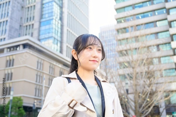 Fototapeta スーツを着てビル街に立つ20代フレッシャーズのビジネスウーマン