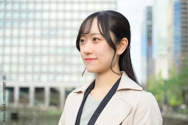 Fototapeta スーツを着てビル街に立つ20代フレッシャーズのビジネスウーマン