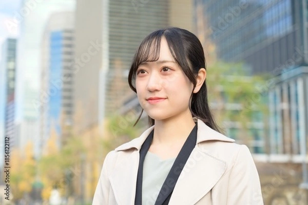 Fototapeta スーツを着てビル街に立つ20代フレッシャーズのビジネスウーマン