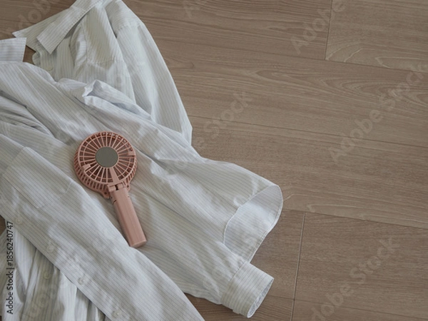 Obraz 家のベランダの床にある夏用のシャツと携帯扇風機の様子