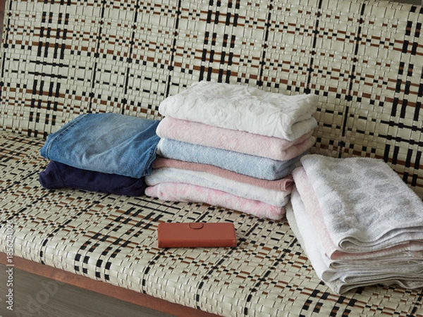 Obraz 家のリビングのソファーの上にあるバスタオルと携帯電話