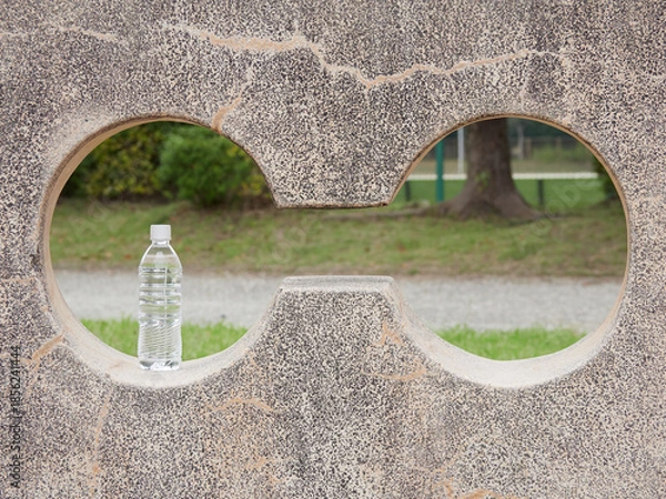 Obraz 昼の公園の石垣に置いてあるペットボトルの水の様子