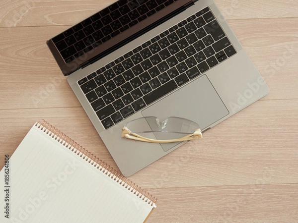 Obraz 机の上にあるノートブックとメガネとノートパソコンの様子