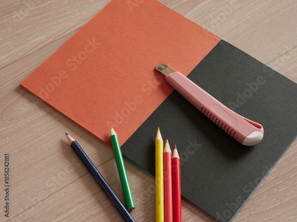 Obraz 色画用紙の上にあるたくさんのカラフルな色鉛筆とカッターナイフの様子