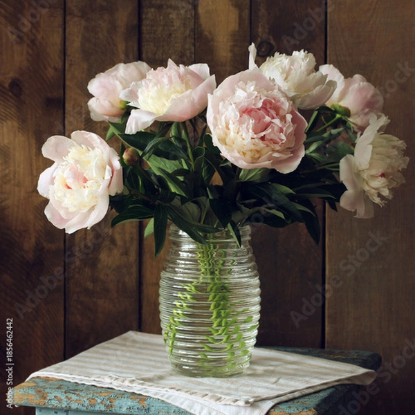 Fototapeta Peonies bouquet in glass vase on rustic wood background