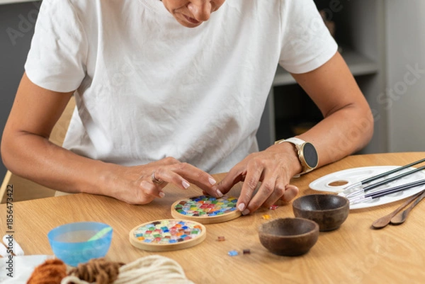 Obraz Woman creating decorative coasters in a relaxed home craft setup. Emphasizes precision, material control, and thoughtful artistic routine.