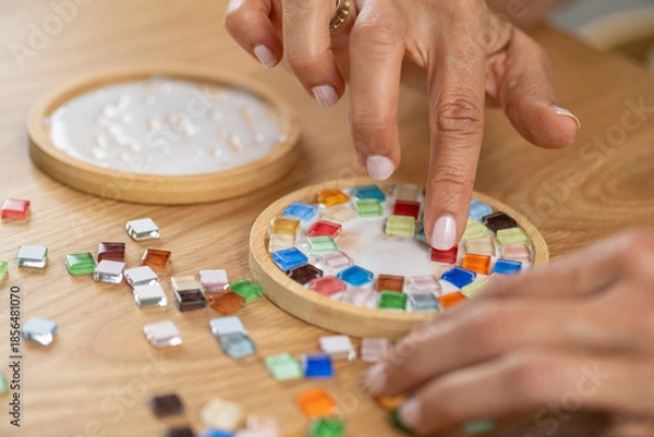 Obraz Attaching small elements to coaster surfaces using glue. Emphasizes careful placement, focus, and structured artistic assembly.