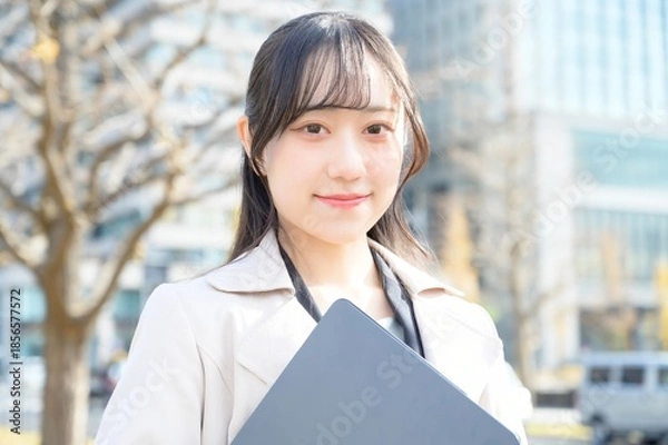 Fototapeta オフィス街でノートパソコンを持つビジネスウーマン
