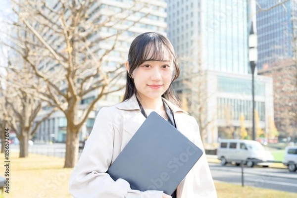 Fototapeta オフィス街でノートパソコンを持つビジネスウーマン