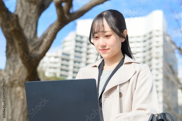 Fototapeta オフィス街でノートパソコンを持つビジネスウーマン