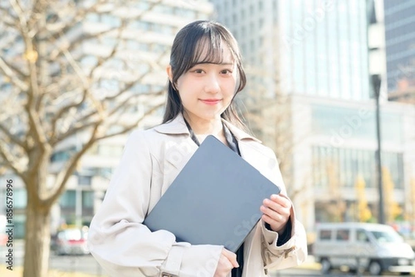 Fototapeta オフィス街でノートパソコンを持つビジネスウーマン