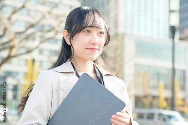 Fototapeta オフィス街でノートパソコンを持つビジネスウーマン