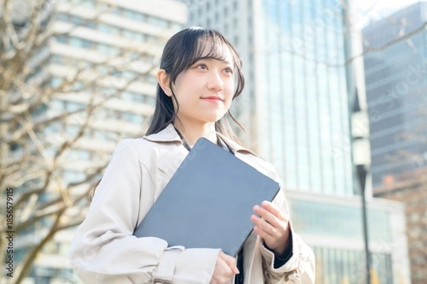 Fototapeta オフィス街でノートパソコンを持つビジネスウーマン
