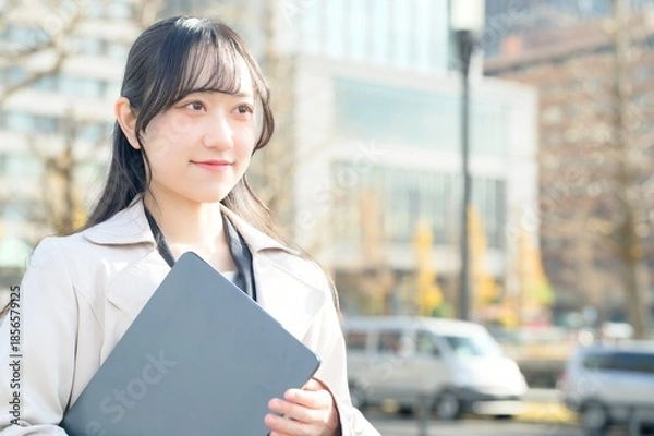 Fototapeta オフィス街でノートパソコンを持つビジネスウーマン