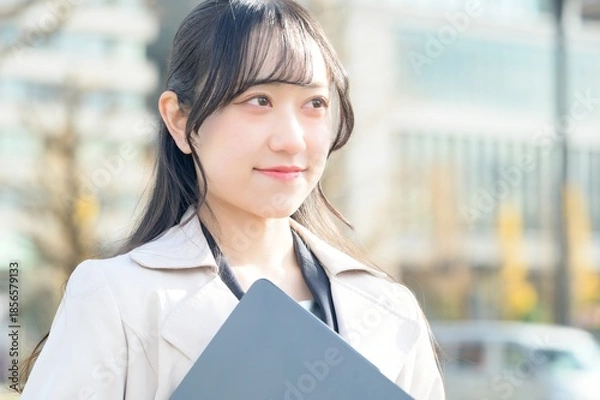 Fototapeta オフィス街でノートパソコンを持つビジネスウーマン