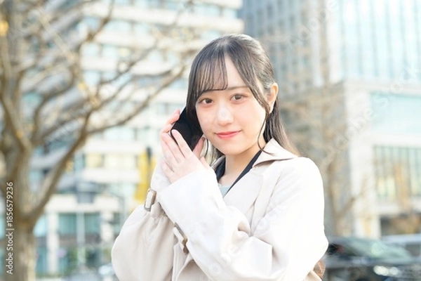 Fototapeta オフィス街でスマホを使用する20代のビジネスウーマン